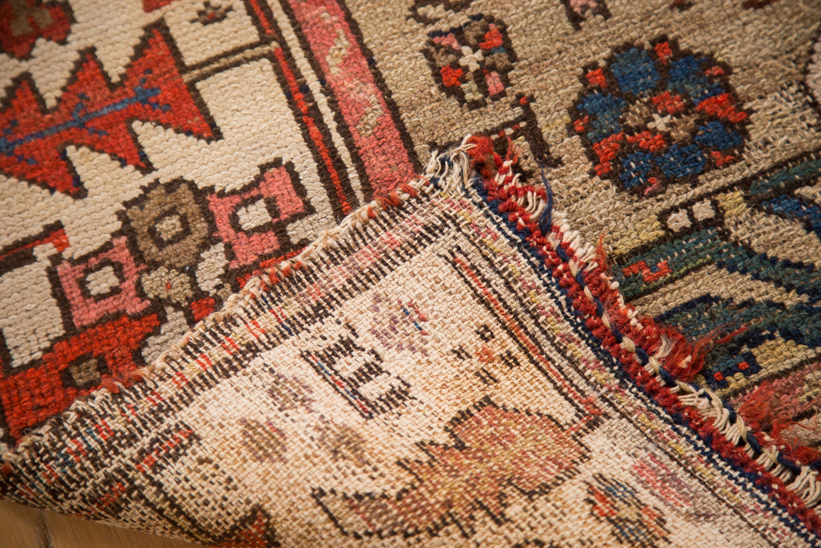 Hand-knotted foundation, geometric pile, and distressed red, blue edge.